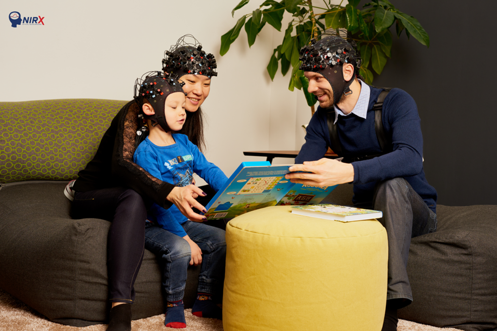 Parents and a child wearing mobile fNIRS devices during reading